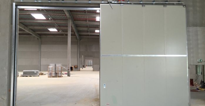 Porte coupe-feu coulissante Porte de séparation ouverte dans un espace intérieur d'entrepôt.