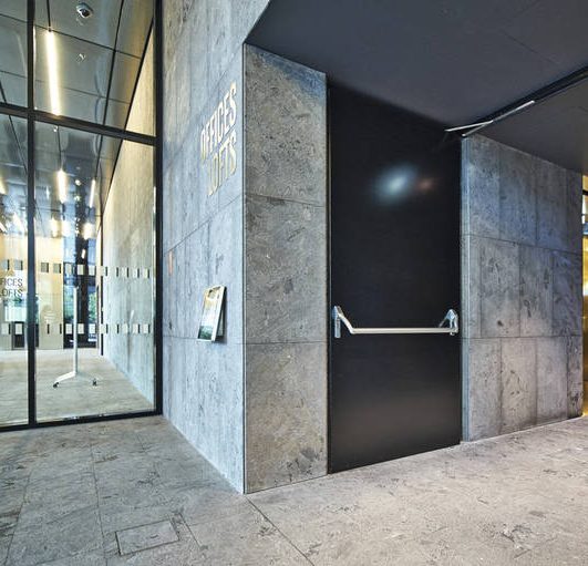 Porte métallique de secours Porte noire dans un hall moderne avec des murs en marbre et des fenêtres en verre.