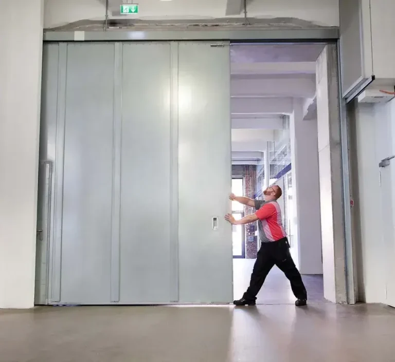 Vérification porte coupe-feu coulissante Personne en train d’ouvrir une grande porte coulissante dans un espace intérieur moderne.